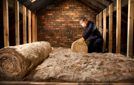 An installer fitting loft insulation