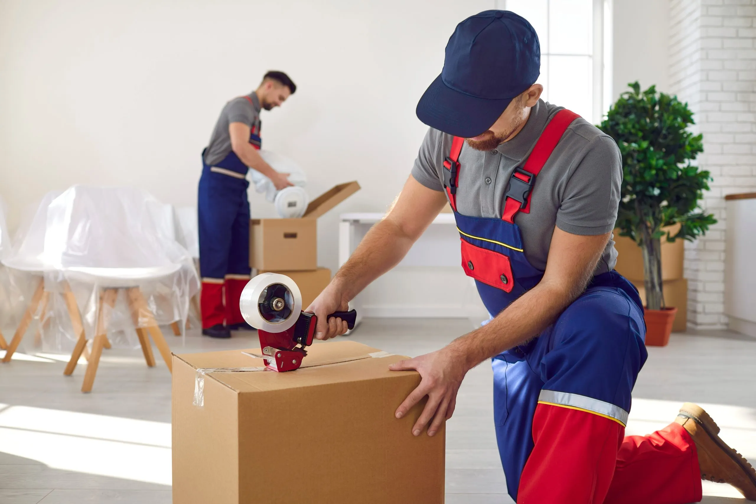 Removal team packing and taping boxes ready for a house move