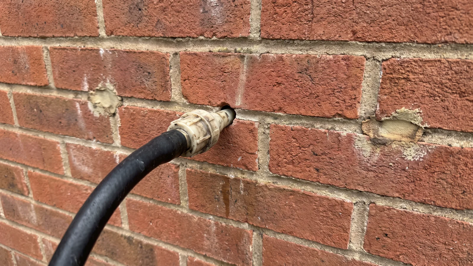 Cavity wall insulation being injected through drilled holes in a UK house wall